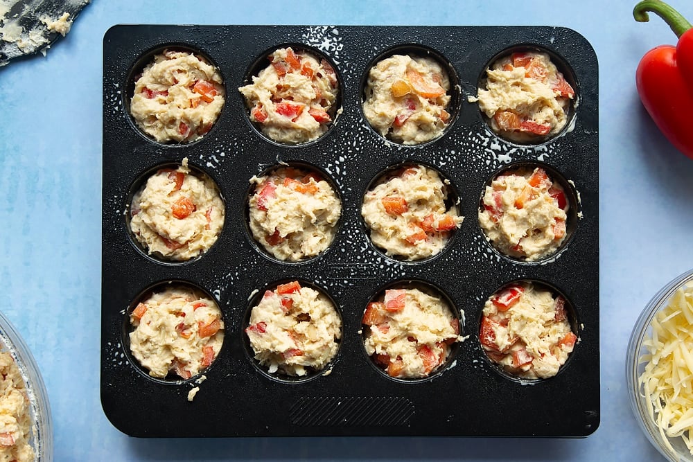 Adding the cheese and red pepper muffins mixture to the muffin tray. 