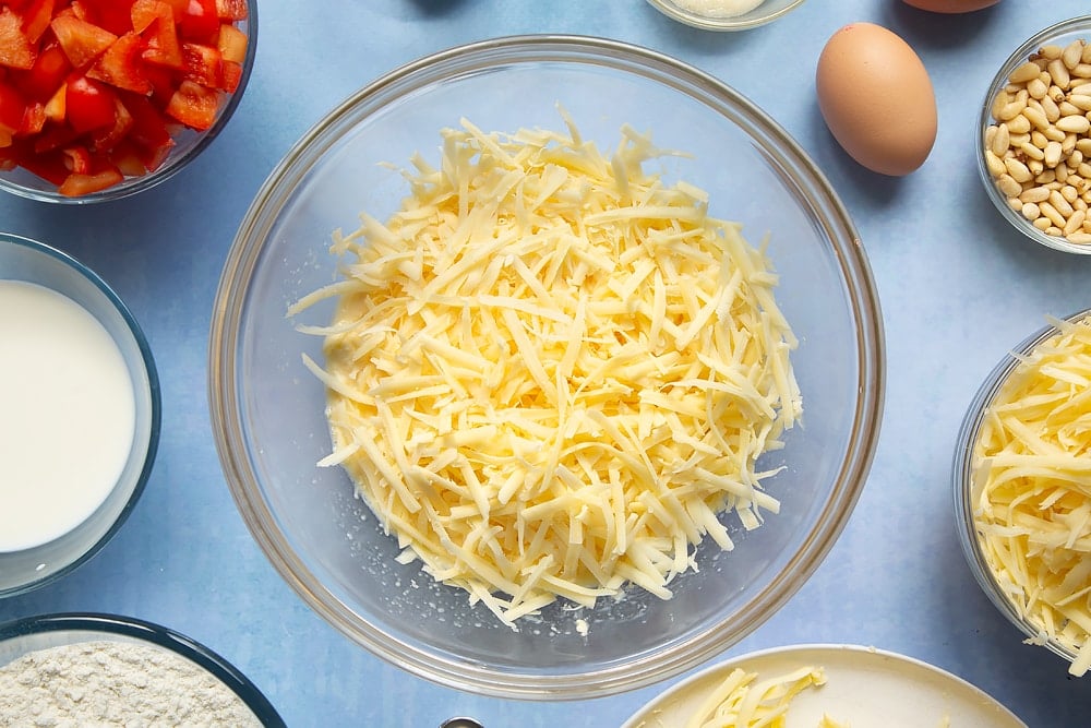 Adding some additional cheese to the cheese and red pepper muffins mixture.