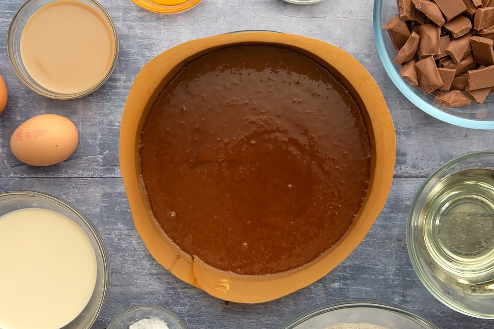 Adding the galaxy chocolate cake mix to a grease lined cake tin. 