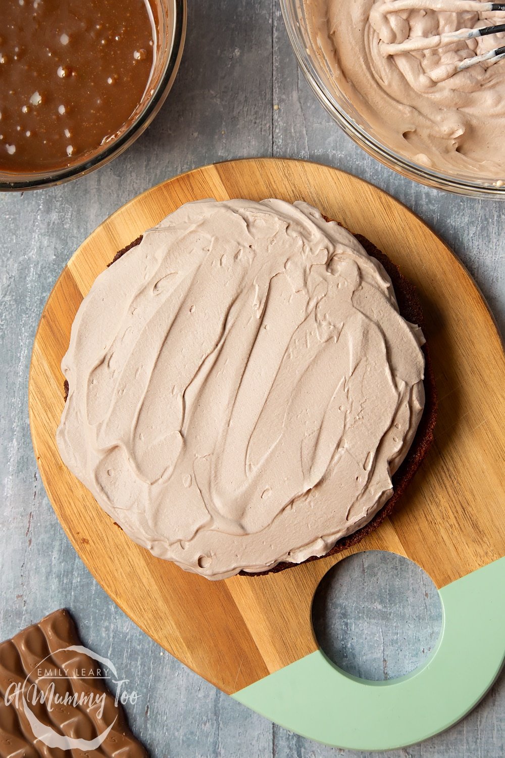 galaxy chocolate cake sponge with baileys cream being added to the top using a flat knife. 