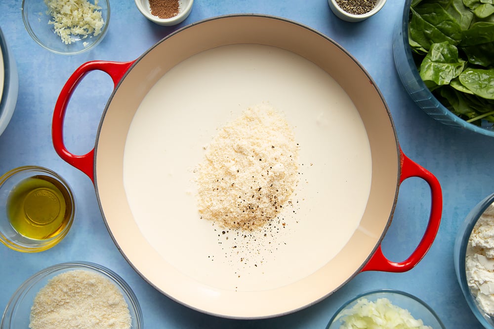 Overhead shot of cream, salt, pepper, and parmesan in a red pan