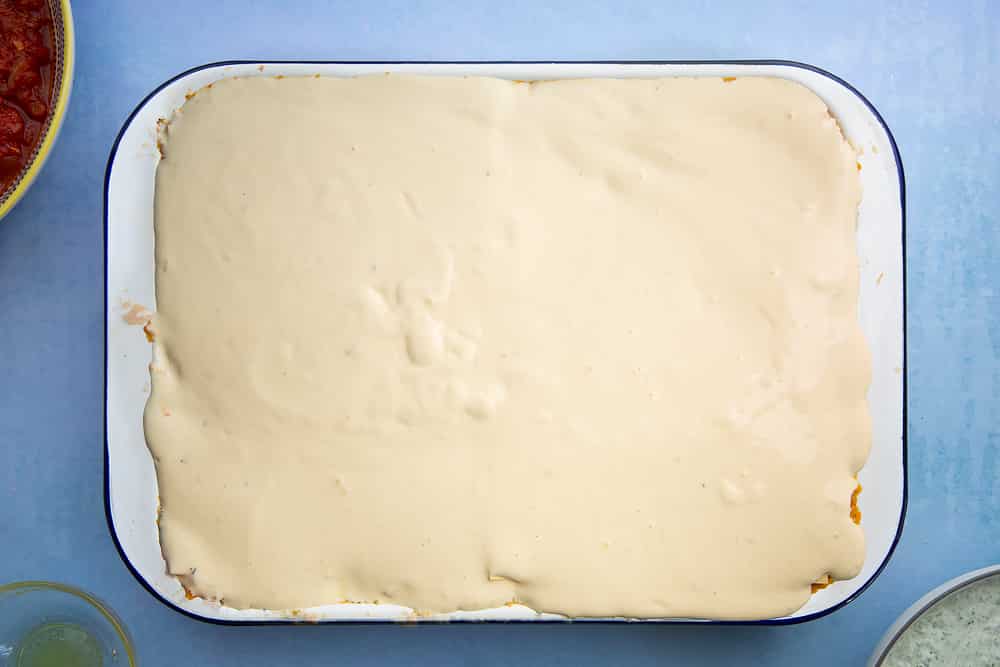 Overhead shot of white sauce in a lasagne dish
