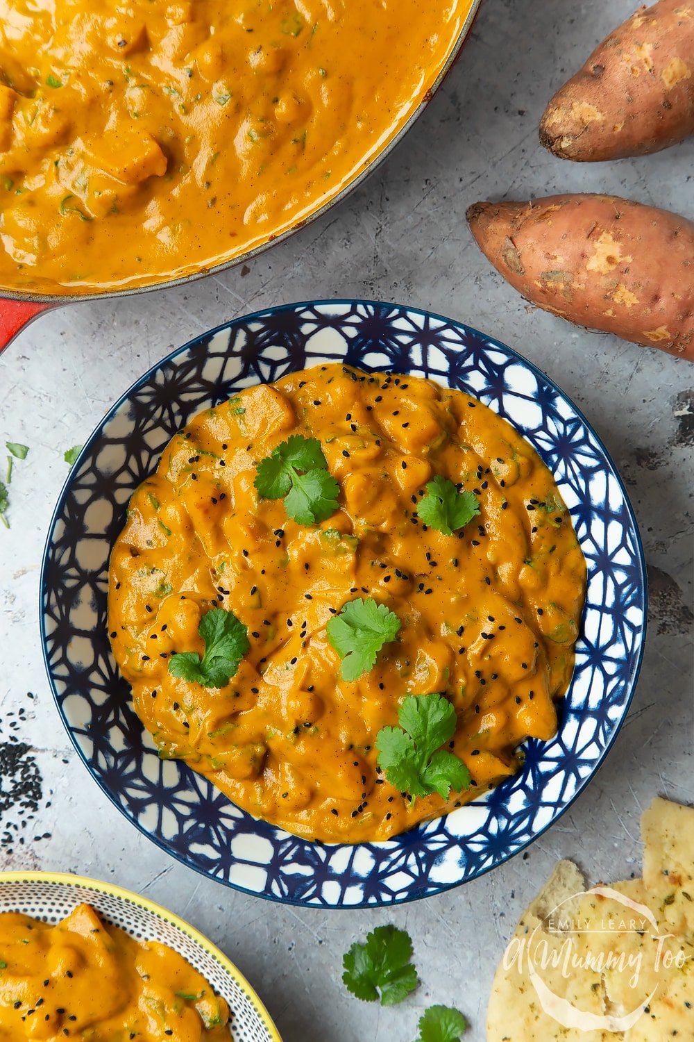 A completed bowl of butternut squash and chickpea curry served in a dark blue decorative bowl topped with coriander. 