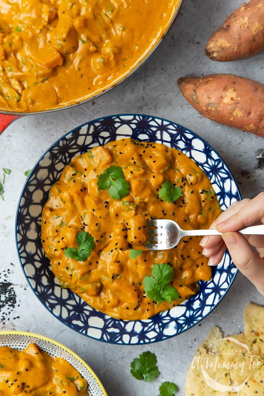 A fork into a finished bowl of butternut squash and chickpea curry.