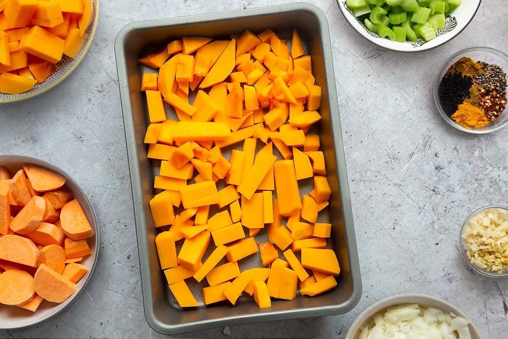 Adding butternut squash to the baking tray. This will be baked and used in the butternut squash and chickpea curry. 