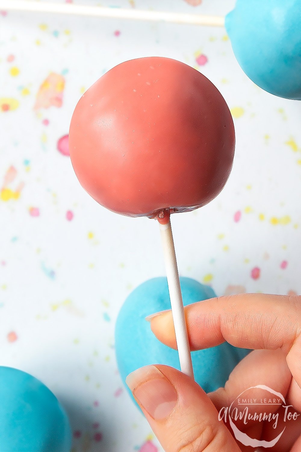 een hand houdt een pastel cake pop van een cake pop boeket.