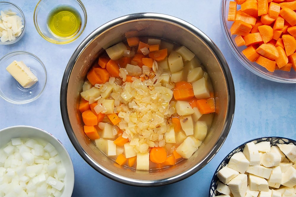 Adding the fried onions and garlic to the pan of slow cooked parsnips and carrots.