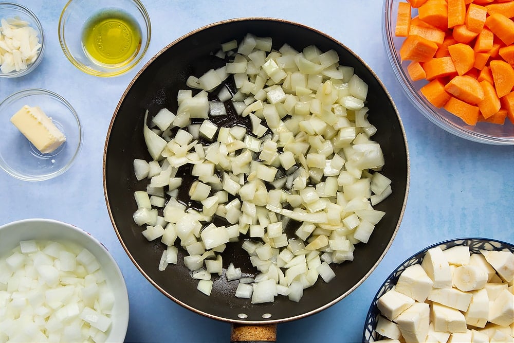 Chopped onions and garlic being added to the pan on a medium heat.