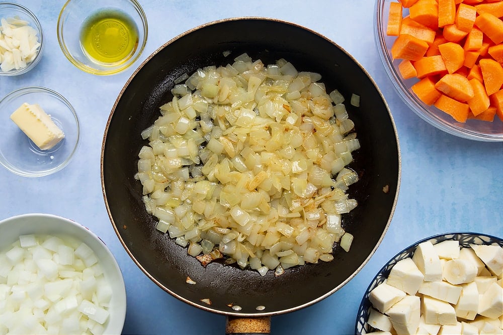Chopped onions and garlic having been cooked on medium heat in a pan until they reach a golden brown color. 