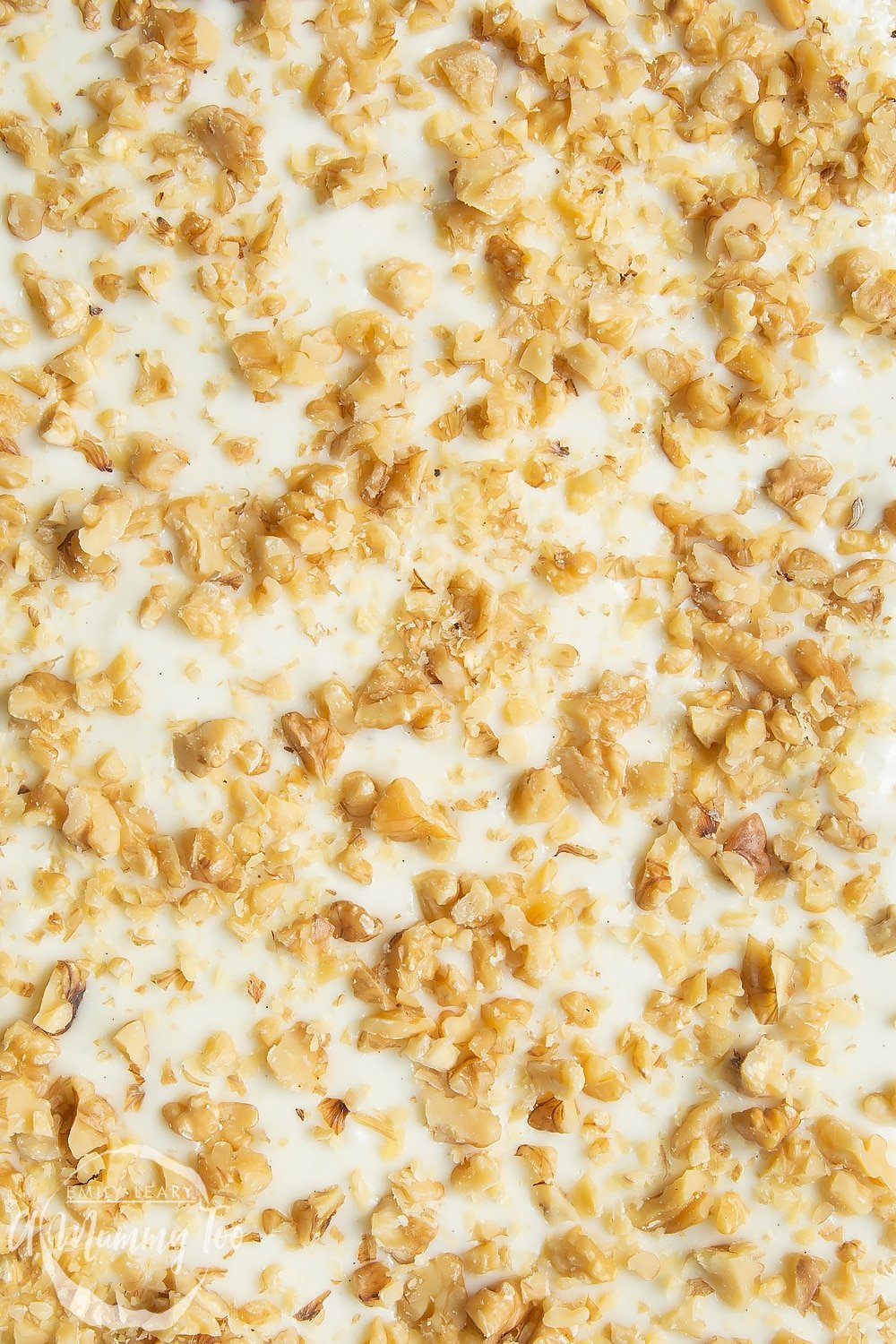 An overhead view of the carrot cake tray bake where you can see the texture of the frosting and chopped walnuts. 