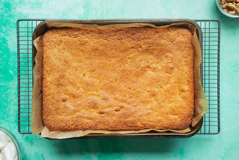 The carrot cake tray bake cooling on a wire rack having been baked in the oven. 