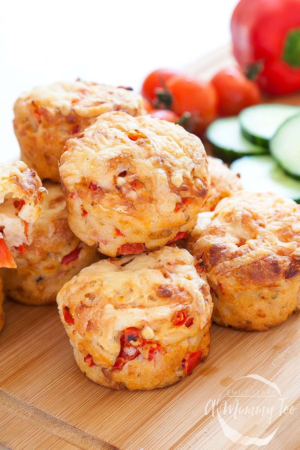 Close up of some Cheese and red pepper muffins. In the background there's different ingredients used for this recipe. 
