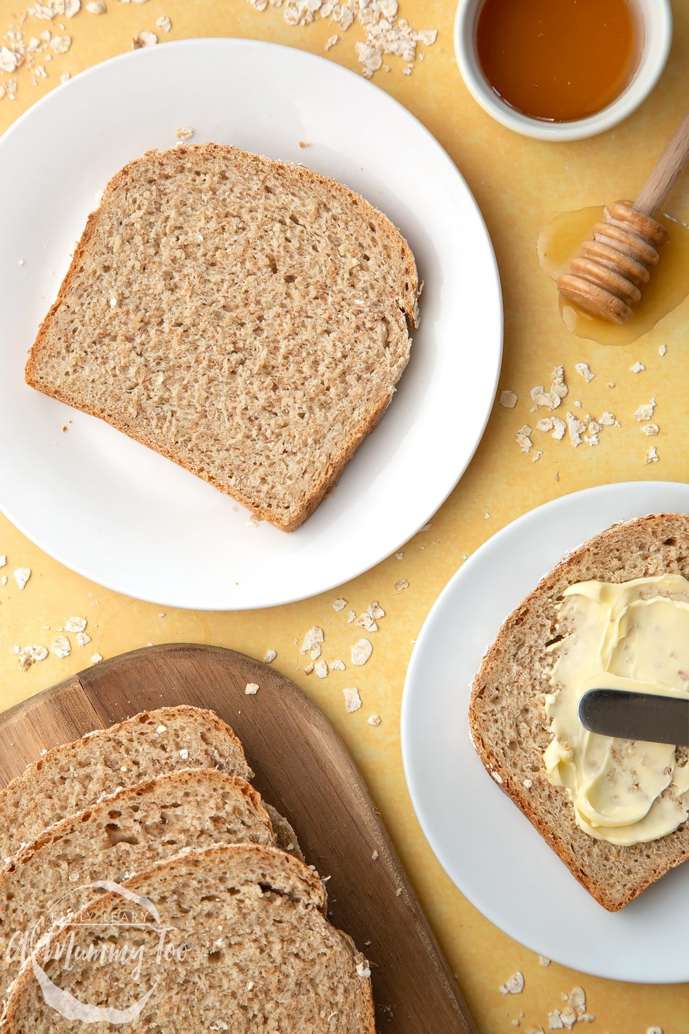 Overhead shot of light honey and oat bread served on a white plate with a mummy too logo in the lower-left corner