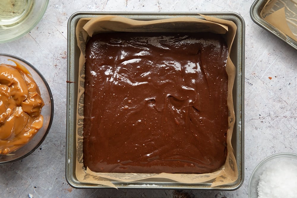 Evenly spread gooey salted caramel brownies mixture in a lined cake tin