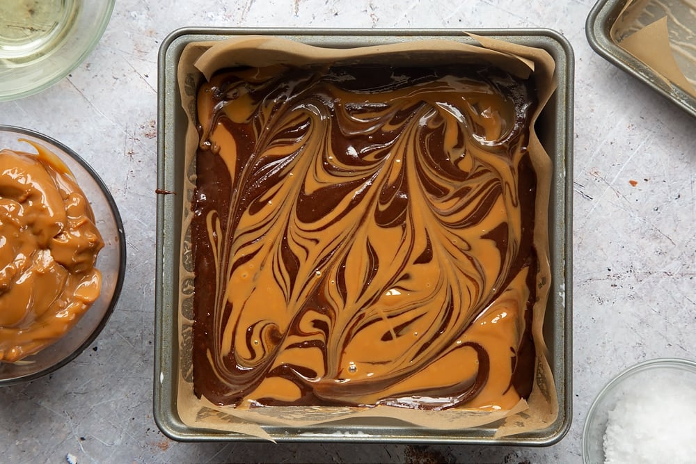 Swirling the mixture with the handle of a spoon to create gooey salted caramel brownies