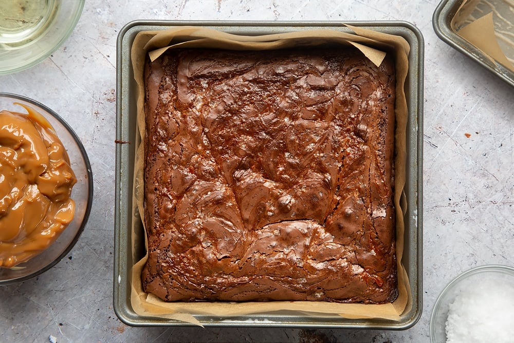 Gooey salted caramel brownies in a cake tin having been baked in the oven. 