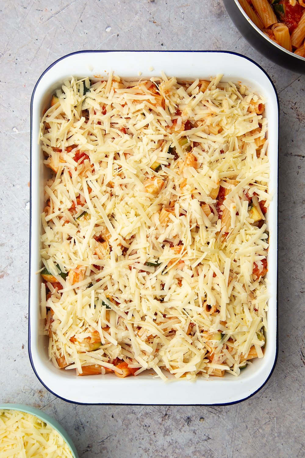 A tray of halloumi pasta bake with grated cheese on the top.