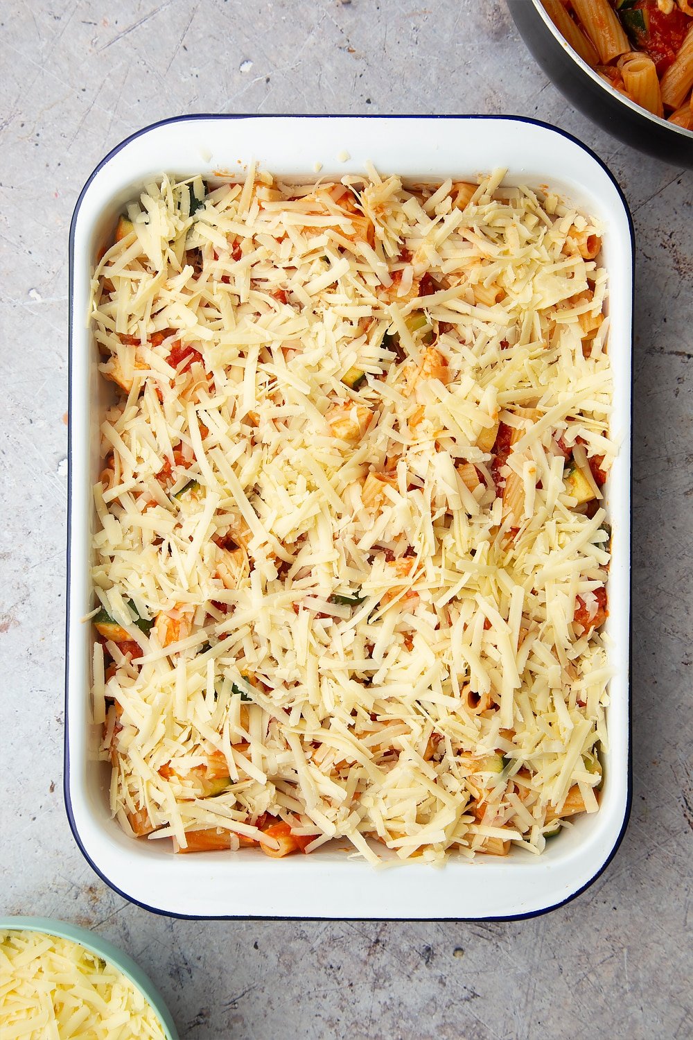 A tray of halloumi pasta bake with grated cheese on the top. 