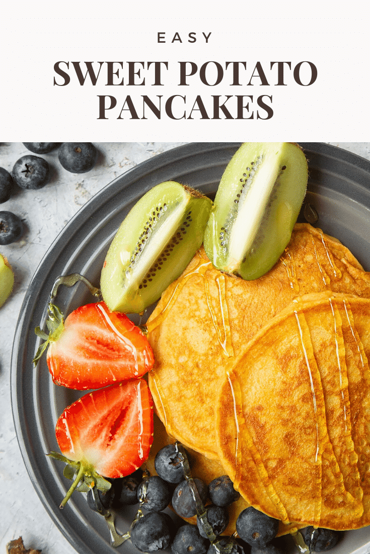 Close up overhead shot of the sweet potato pancakes on a black plate at the side of the pancakes there's some chopped fruit. Meanwhile at the top of the image there's some text describing the image for Pinterest. 