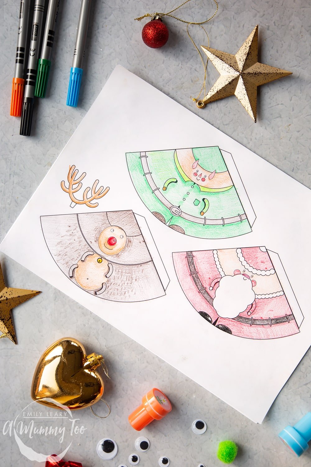 A sheet of A4 paper which has the 3 characters; Santa, elf and reindeer all coloured in with pencils and ready to be cut out and assembled, 