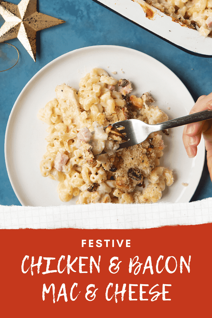 A portion of chicken and bacon mac and cheese served on a small white plate with a fork digging in. A tray containing more of the pasta is shown to one side. Caption reads: festive chicken & bacon mac & cheese