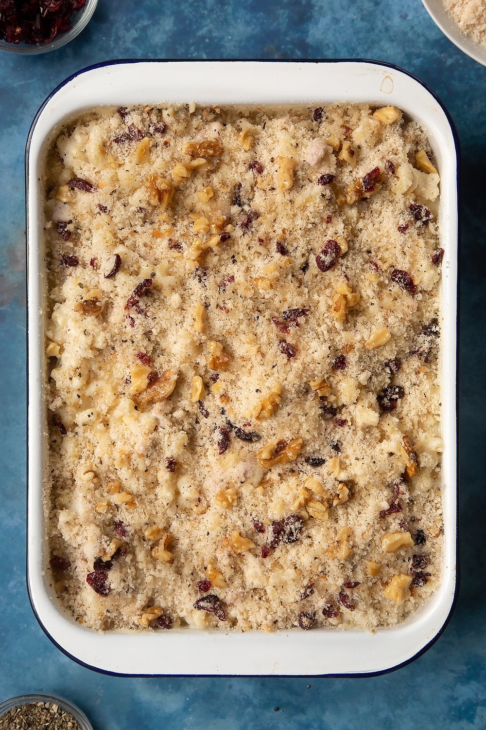 A large roasting pan filled with chicken and bacon mac and cheese, topped with a crumb made from breadcrumbs and drizzled with olive oil.