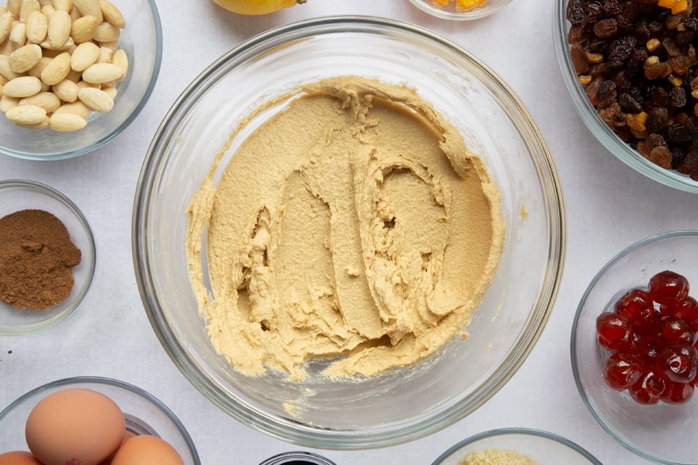 brown sugar and butter creamed together in a large clear bowl surrounded by ingredients in smaller clear bowls.