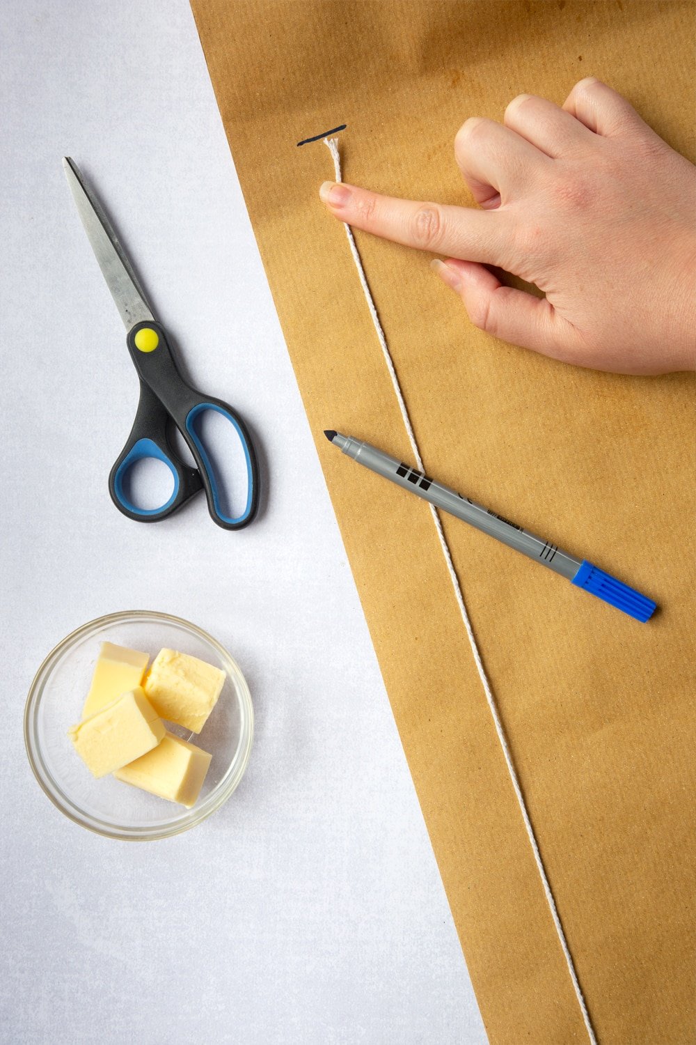 Measuring the length of brown paper required using the string previously cut in the Idiot's guide to lining a Christmas cake tin tutorial. 