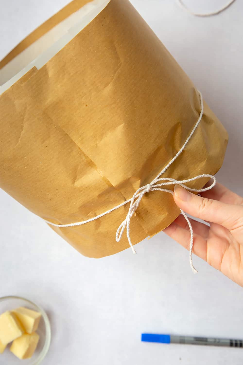 Adding the string to the outside of the brown paper to keep it fixed in place on the outside of the baking tin. 