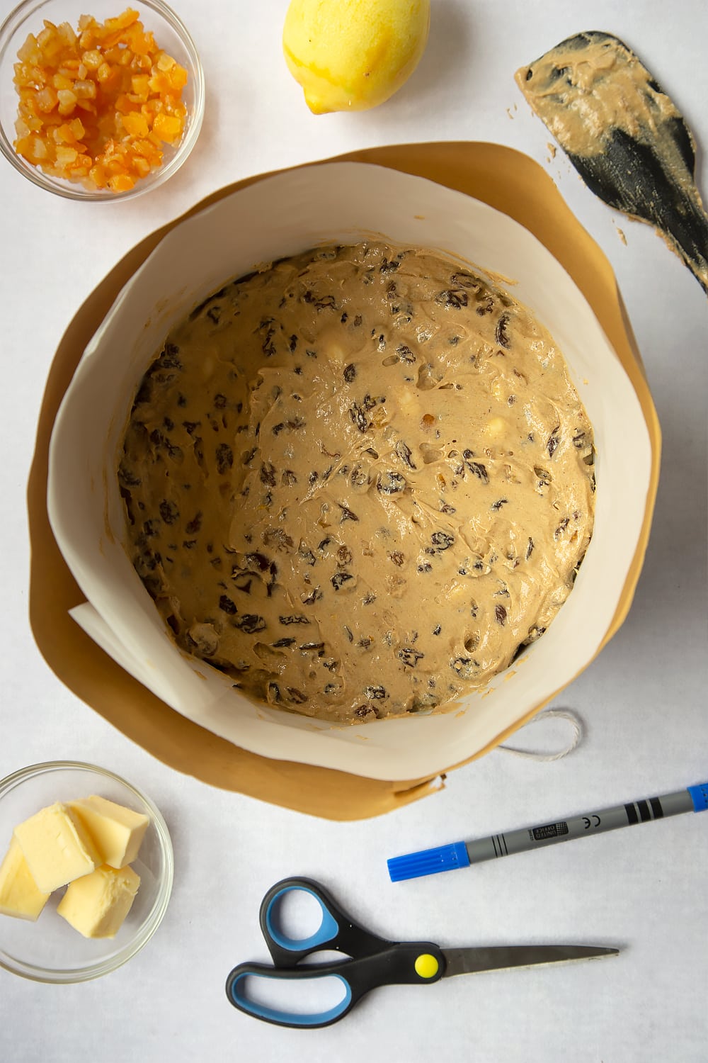 Cake mixture being added to the baking tin which is now fully lined with both brown paper and baking paper. 