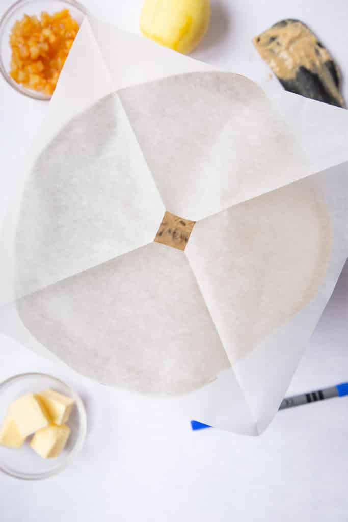 christmas fruit cake in a cake tin covered with a piece of greaseproof paper with a hole cut at the top. 