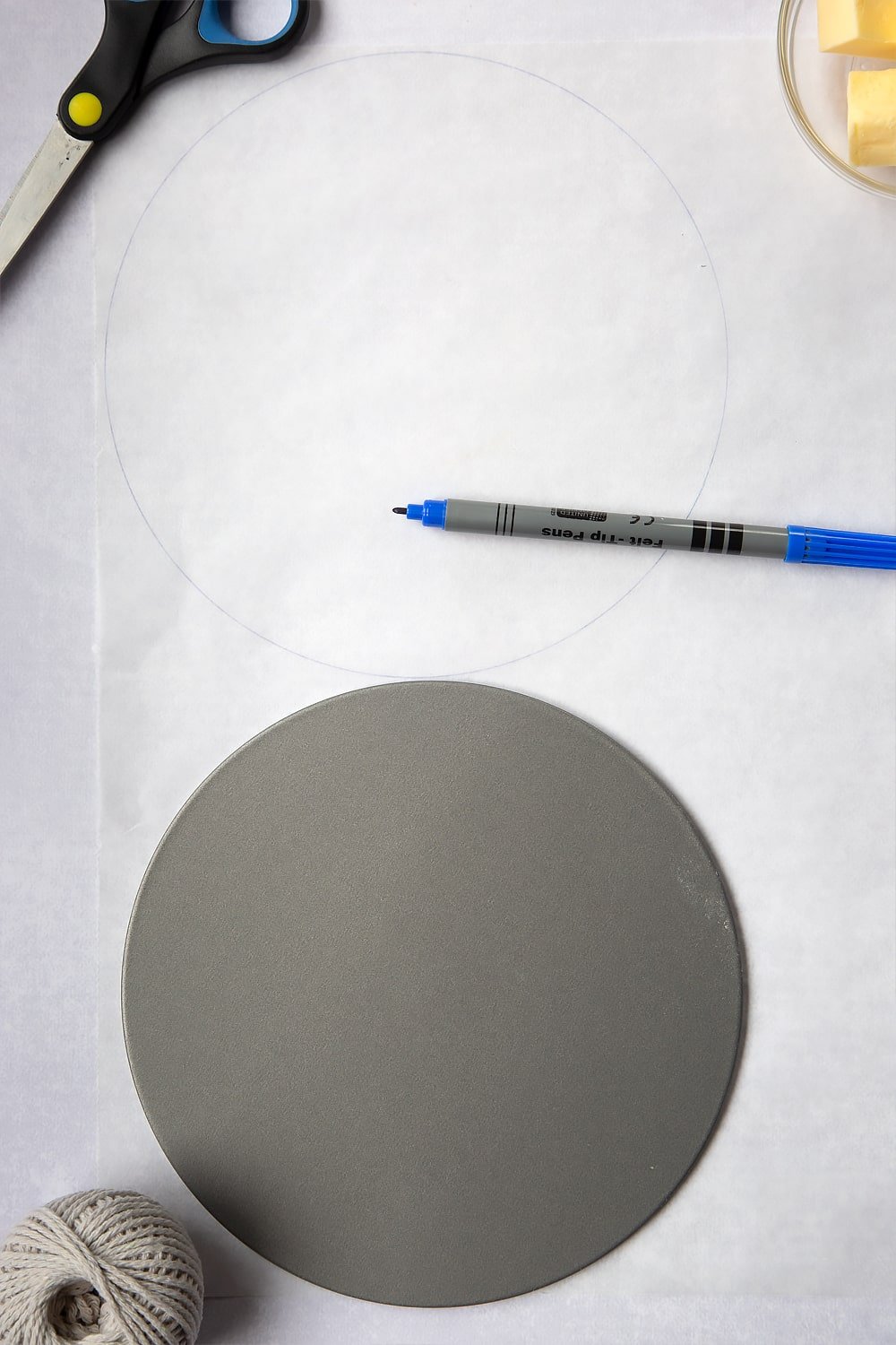 The first step in How to line a Christmas cake tin. An image of a circle which has been drawn by a pen around the cake tin. 