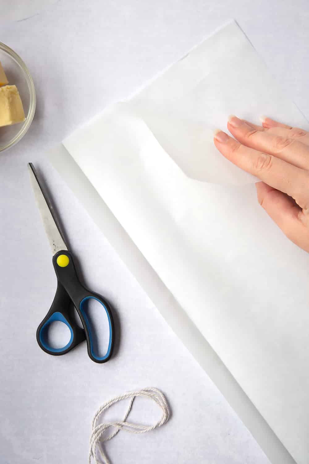 Folding the paper along its length to double the thickness of the strip. Scissors and string have been left to the side to decorate the image. 