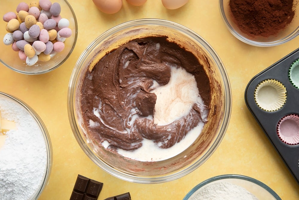 Overhead shot of chocolate muffin mix with milk in a large clear bowl