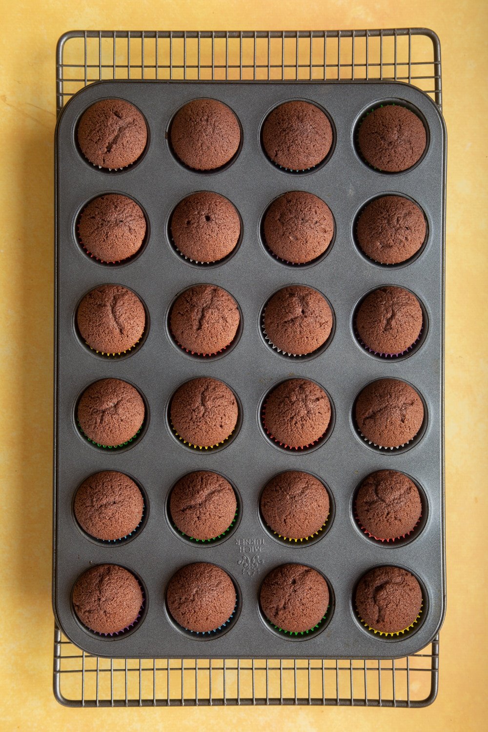 Overhead shot of chocolate muffin in a mix mini cupcake pan on a baking rack