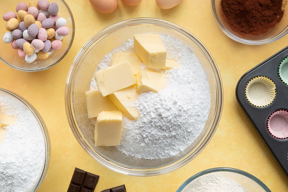 Overhead shot of butter and icing sugar in a large clear bowl