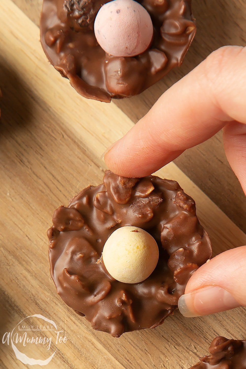 Overhead shot of a hand holding a muesli chocolate Easter nest with a mummy too logo in the lower-left corner