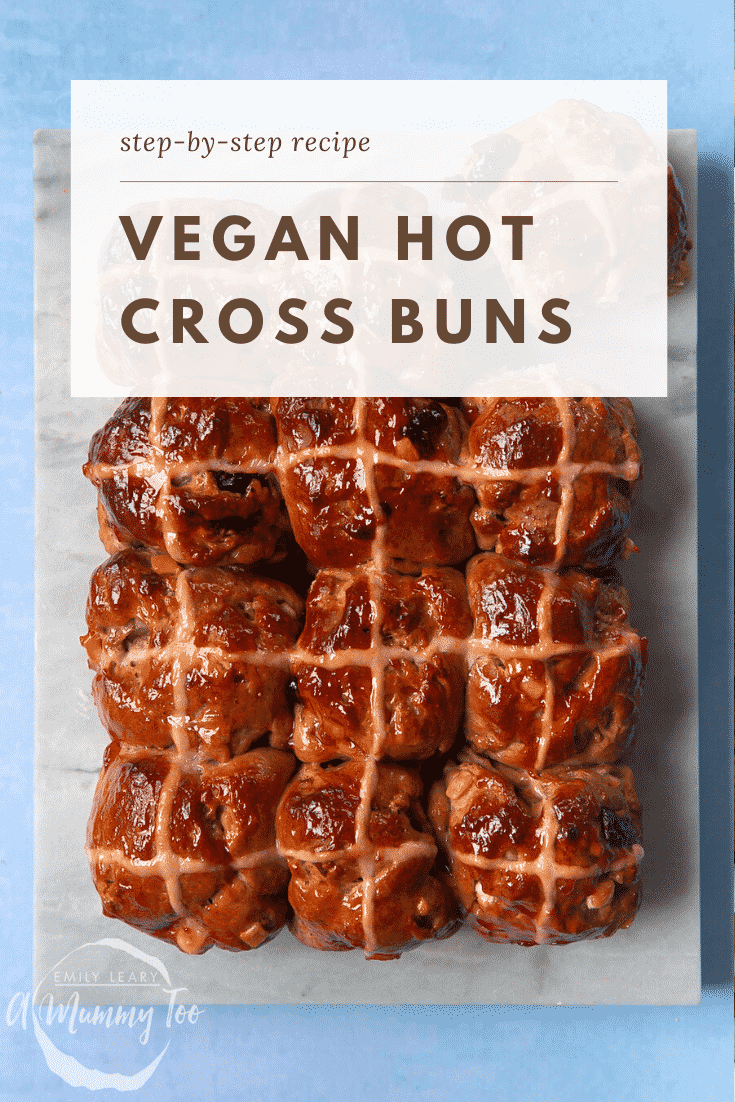 12 vegan hot cross buns on a marble board, brushed with jam. Caption reads: step-by-step recipe vegan hot cross buns