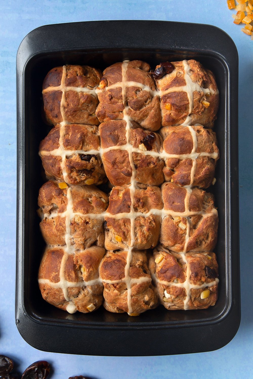 Freshly baked vegan hot cross buns in a baking tray.