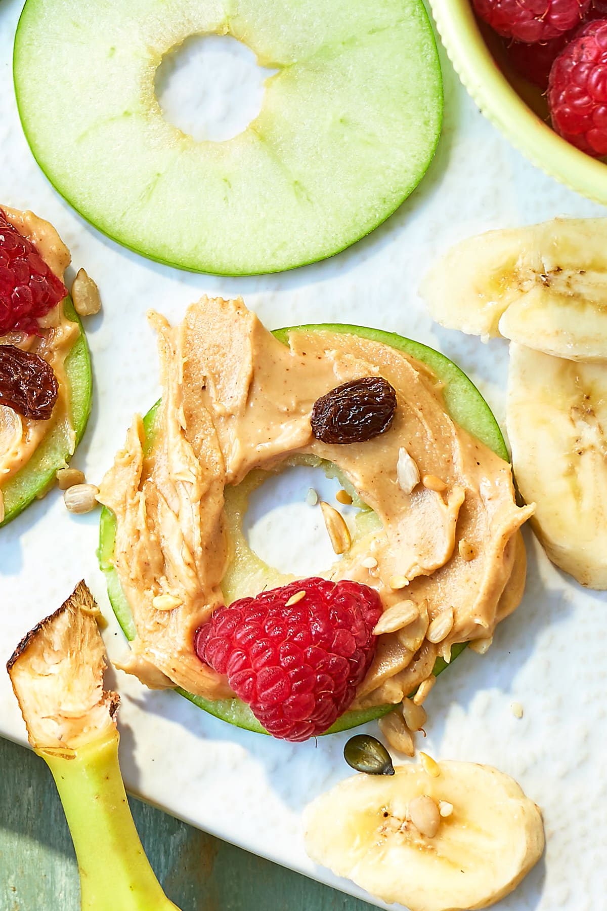 Close up of an apple slice with peanut butter on a white board.