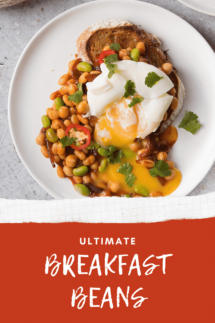 Breakfast beans with chilli, chickpeas and edamame served on sour dough toast with a poached egg on top, the yolk running onto the plate. Caption reads: ultimate breakfast beans.