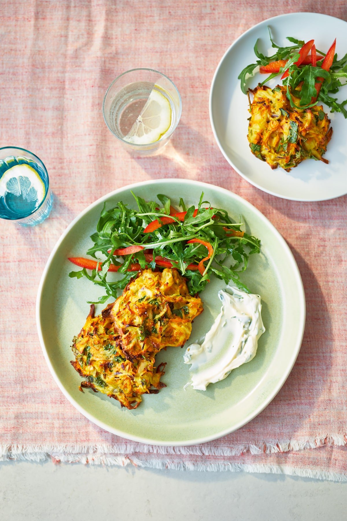 Two plates topped with carrot patties and a rocket and pepper salad.