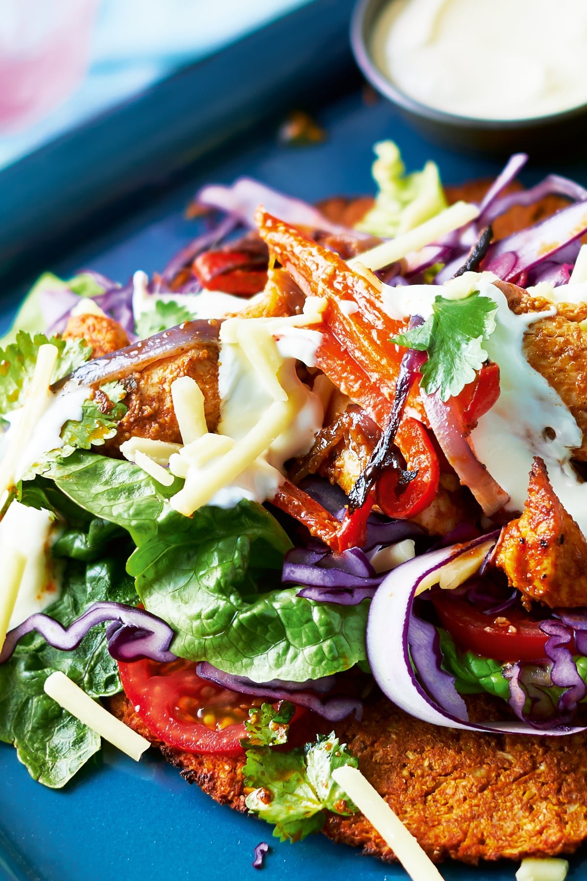 A close up of the filling of a cauliflower fajita with salad and chicken on a blue tray. 