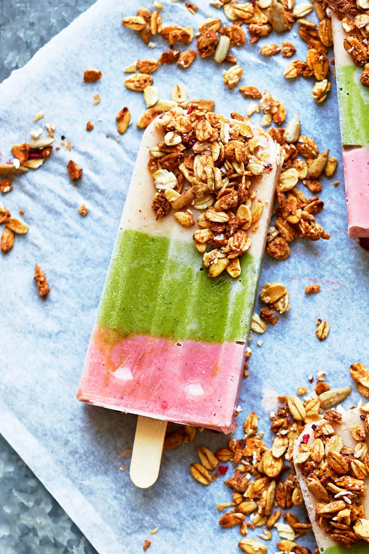 A fruit and veg lollies on a granite board, dipped in granola.