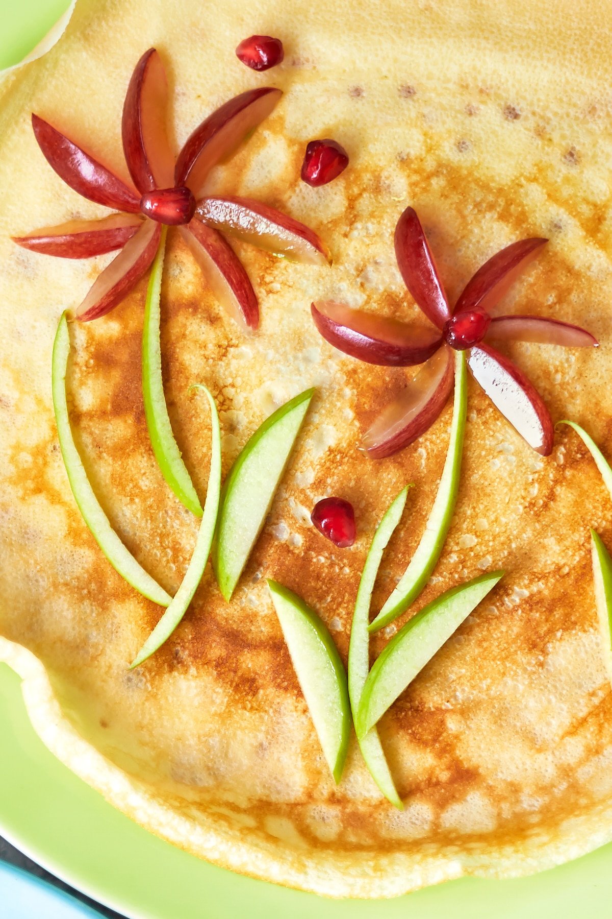 A crepe-style pancake is decorated with fruit to resemble flowers.