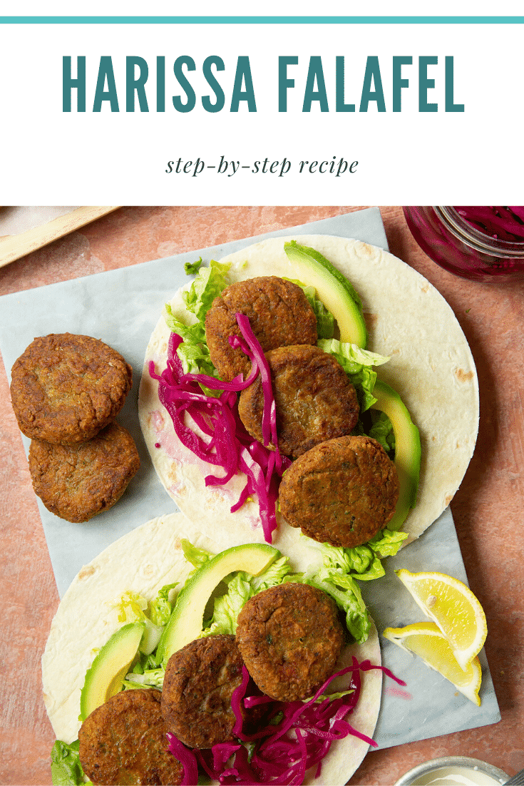 Two harissa falafel wraps arranged on a marble board with pickled cabbage and salad. The text caption reads, harissa falafel.