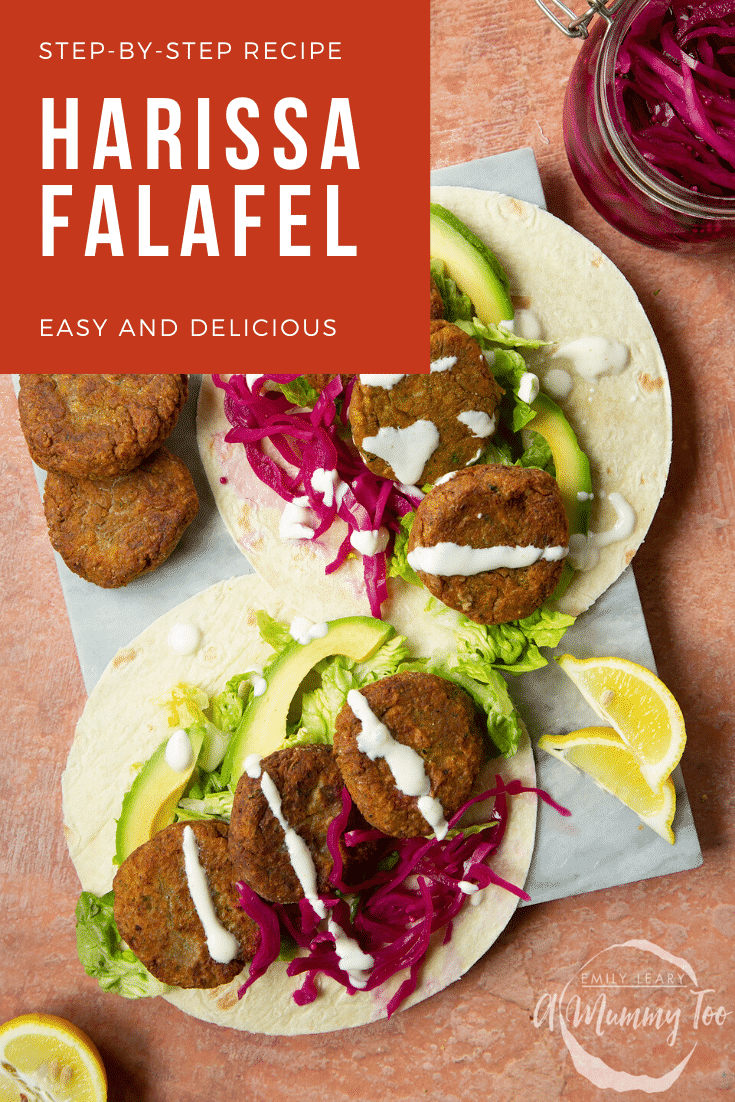 Two harissa falafel wraps arranged on a marble board with pickled cabbage and salad, drizzled with tahini dressing. The text caption reads, harissa falafel - easy and delicious.