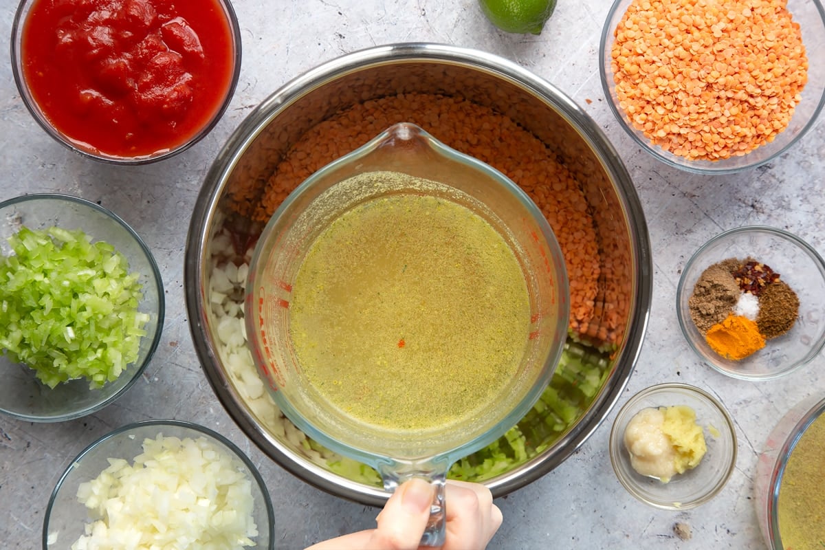 Overhead shot of a hand holding hot stock in a measuring cup