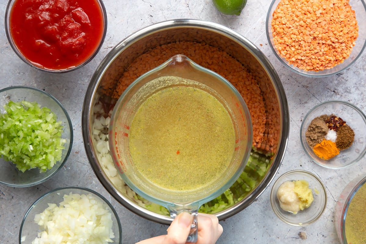 Overhead shot of a hand holding hot stock in a measuring cup 