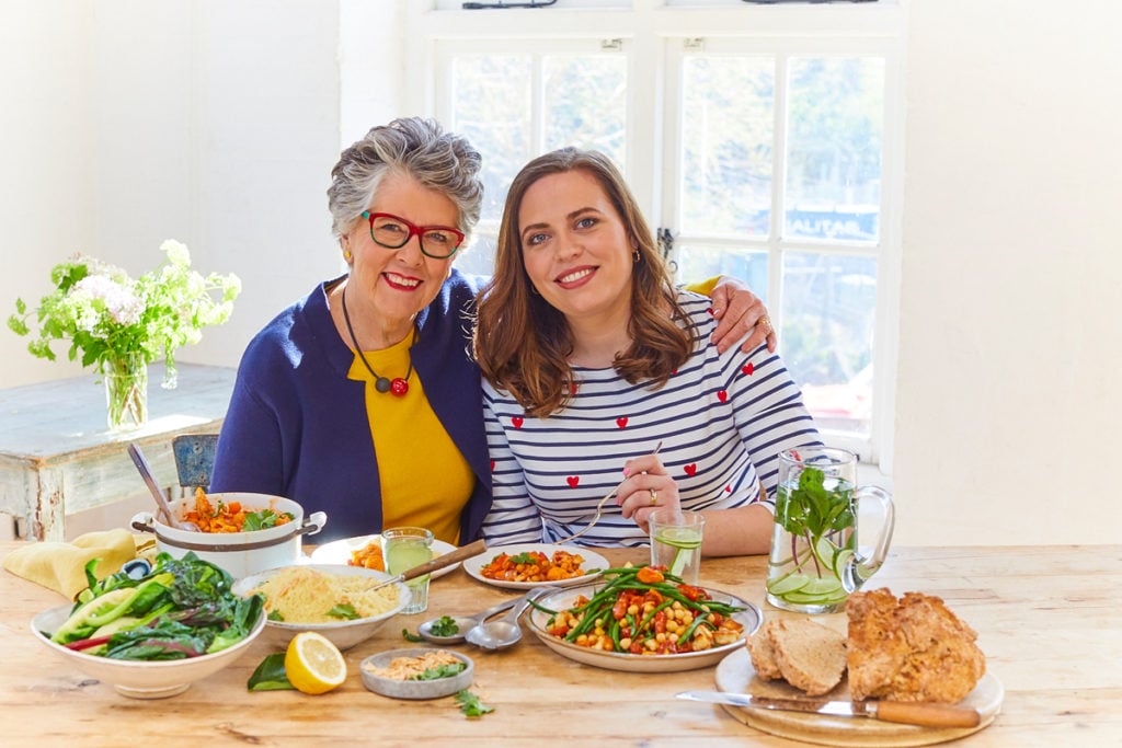 Prue Leith and Peta Leith sitting at a dinner table with dishes from The Vegetarian Kitchen